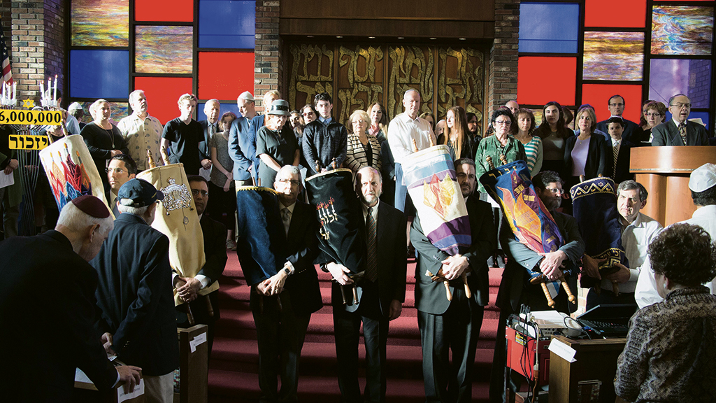 In 2017 survivors’ son Cantor Sam Weiss sings at the JCC of Paramus as local leaders carry Torah scrolls rescued from the Holocaust. (JFNNJ)